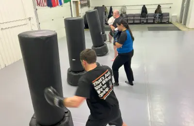 People practicing kicking and punching on heavy bags