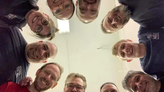 Group of people standing in a circle, smiling down at the camera