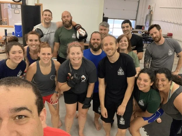 A large group of martial arts students posing together on the training mats after class